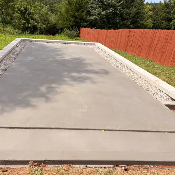 Raised concrete patio slab poured against a privacy fence