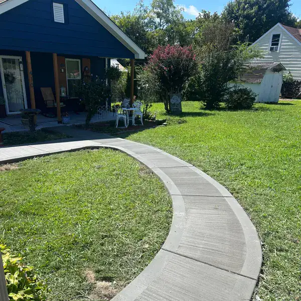 Curved concrete walkway cut through a front lawn