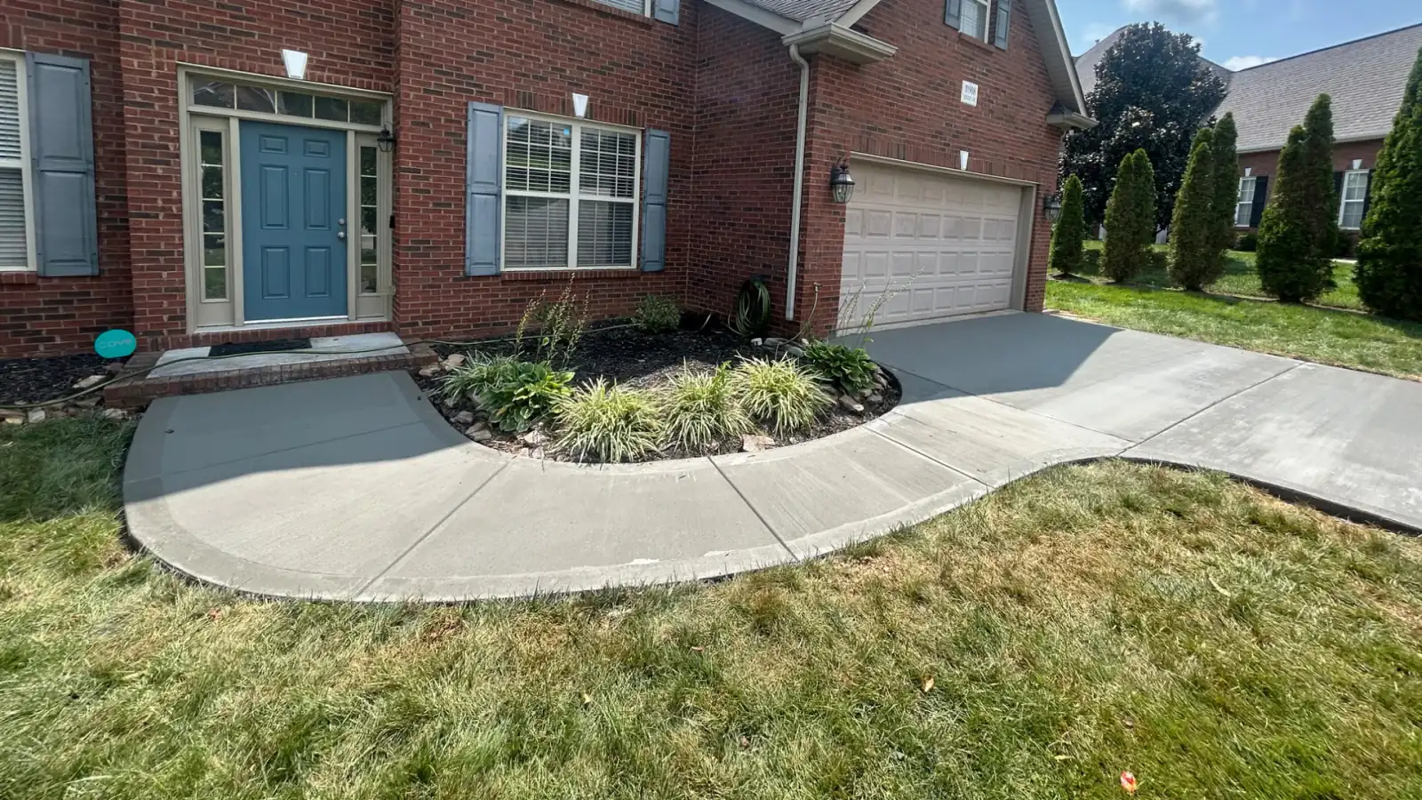 A curved concrete walkway and driveway apron at an East Tennessee brick home